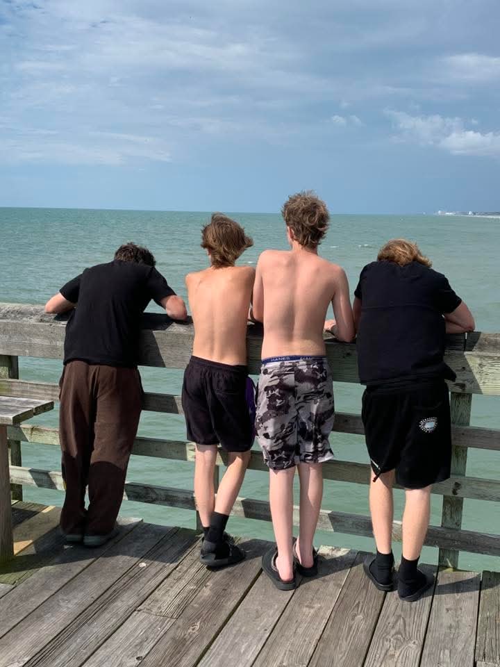 Four young men standing on a wooden pier viewing 1st time the ocean Myrtle Beach